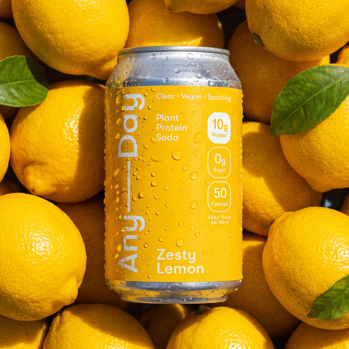 Anyday Zesty Lemon Plant Protein Soda - Dose mit gelbem Etikett liegt auf Zitronen