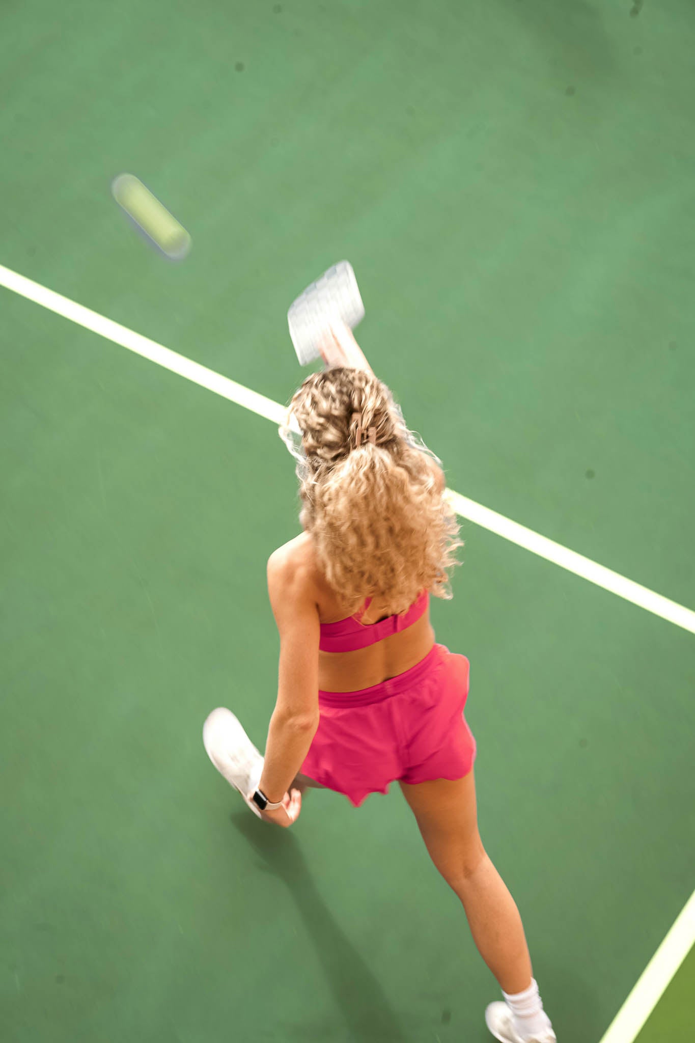Sportliche Frau beim Tennisspielen auf einem grünen Tennisplatz.